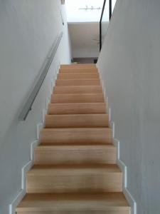una scala con pareti bianche e pavimenti in legno di Muji Designer Suite a Jeram