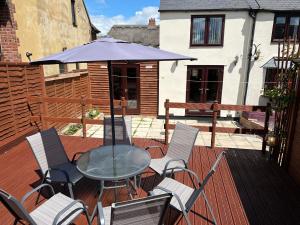 un patio con mesa, sillas y sombrilla en 3 Bed Cottage-Parking-Garden-Free Hot Tub Weekends en Gloucester
