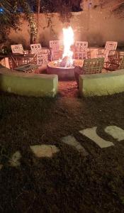 a fire in a yard with chairs and a fire pit at Nour El Waha Hotel in Siwa