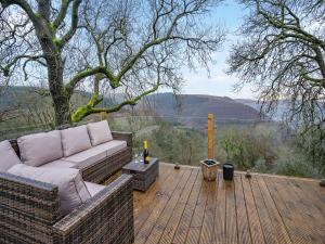 a couch sitting on a wooden deck with a tree at Goshawk Lodge in Abercarn