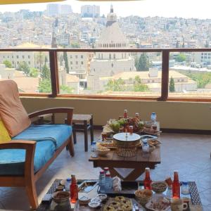 een woonkamer met een tafel en uitzicht op de stad bij Seedi Yousef Hostel & Cafe in Nazareth