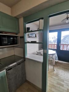 a kitchen with green cabinets and a table and a window at Studio vue montagne proche des pistes in Orcières