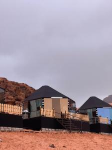 a building with black roofs in the desert at Al Raha Luxury Camp in Wadi Rum
