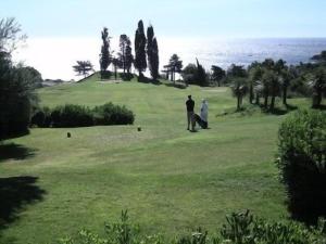 un hombre y una mujer de pie en un campo de golf en AGAY, Cap Esterel, magnifique vue mer panoramique et Esterel, terrasse, piscines, parking, dernier étage, 3 étoiles, en Saint-Raphaël