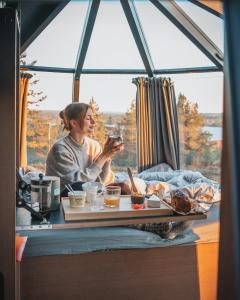 una mujer sentada en una mesa con una comida delante de una ventana en Northern Lodges, en Piteå