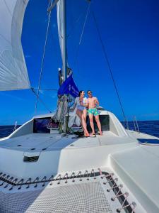 twee mensen zitten achterop een zeilboot bij Sabba Whitesand Catamaran in Fodhdhoo