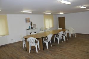 a conference room with a wooden table and white chairs at Pensiunea Martinel in Timisu de Sus