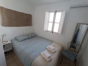 - une petite chambre avec un lit et une chaise dans l'établissement Casa Al-Janda, à Barbate