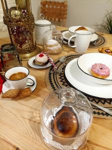 Amira 1899 Luxury Suite في غالاتينا: طاولة خشبية مع أكواب من القهوة وأطباق من الكعك