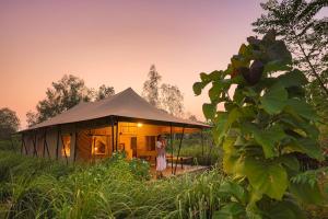 Una donna in piedi davanti a una tenda in un campo di Aalia Jungle Retreat and Spa, Bandarjudh, Haridwar - Araiya Anthology a Dehradun