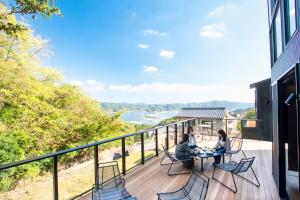 3 personas sentadas en una mesa en un balcón con vistas al océano en Awaji-shima C-Side Dual View - Vacation STAY 88182v, en Minamiawaji