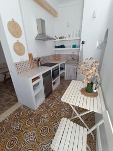 une cuisine avec des comptoirs blancs, une table et des bancs dans l'établissement Casa Al-Janda, à Barbate