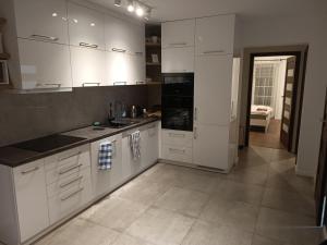 Il comprend une cuisine avec des placards blancs et du carrelage. dans l'établissement Apartament Krucze Łąki, à Kruklanki