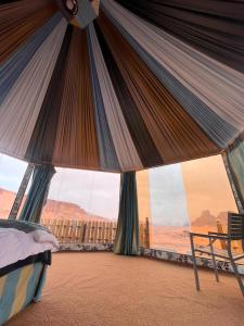 a bed in a tent with a view of the desert at Al Raha Luxury Camp in Wadi Rum