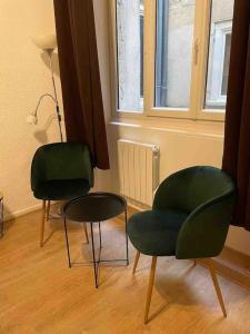 twee groene stoelen en een tafel in een kamer bij LA GRANDE COTE in Lyon
