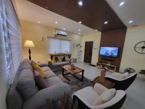 a living room with a couch and a tv at Luxury 3BR Villa w Plunge Pool near SM Batangas City- Instagram-Worthy! in Batangas City