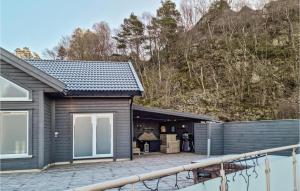 ein schwarzes Haus mit einer Terrasse neben einem Berg in der Unterkunft Stunning Home In Lyngdal With Kitchen in Lyngdal