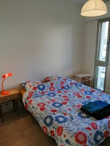 - une chambre avec un lit et une couette colorée dans l'établissement Appartement T3 vue sur rivière, 2 chambres 65M2, à Châteaulin