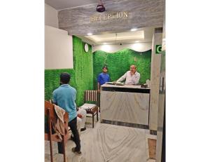 two men standing at a counter in a green room at Hotel Kanha Classic, Kanpur in Kānpur