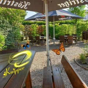 un banc avec un parapluie et des papillons dessus dans l'établissement Hotel Knipper, à Lastrup