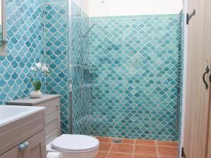 uma casa de banho com um WC e um chuveiro com azulejos azuis em Tucking Cottage em Treffgarne