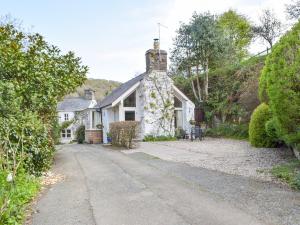 una casa blanca con una chimenea de piedra en una calle en Tucking Cottage, en Treffgarne