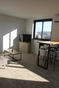 a living room with a table and chairs and a tv at Immeuble rénové au centre d'Auch. in Auch