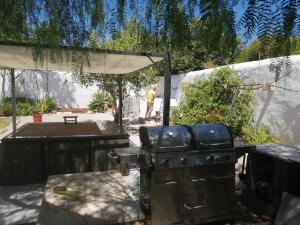 un homme debout dans une arrière-cour avec un grill dans l'établissement Casa Mimosa, à São Brás de Alportel