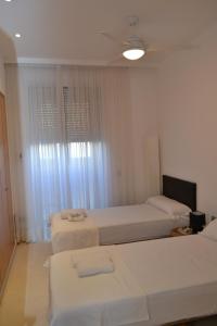 Habitación blanca con 2 camas y ventana en Anka Beach Apartment Patacona en Valencia