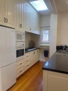uma cozinha branca com electrodomésticos brancos e pisos em madeira em Waterloo Cottage em Hobart