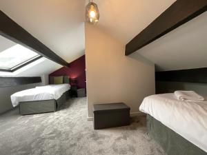 a attic bedroom with two beds and a window at Large 4 double bedroomed townhouse in central Holmfirth in Holmfirth