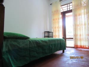 uma cama verde num quarto com uma janela em pumindu homestay em Matara