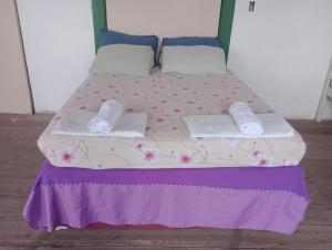 a bed with two pillows and towels on it at Hostel L B in São Luís