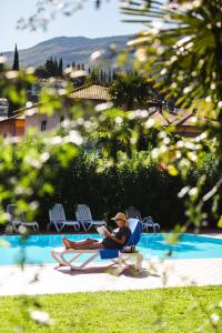 una persona seduta su una sedia a sdraio che legge un libro di Brione Green Resort a Riva del Garda