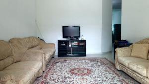 a living room with two couches and a tv at Homestay Ahmad Kuala Kangsar in Kuala Kangsar