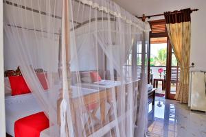 Esprit Bentota في بينتوتا: غرفة نوم مع سرير مظلة مع ستائر بيضاء