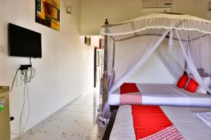 Esprit Bentota في بينتوتا: غرفة نوم مع سرير المظلة مع الوسائد الحمراء