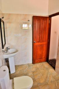 La salle de bains est pourvue d'un lavabo, de toilettes et d'une porte en bois. dans l'établissement Esprit Bentota, à Bentota