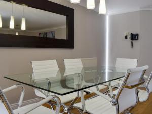 a glass dining room table with white chairs and a mirror at Hollies Cottage 14 -ukc4537 in Martock