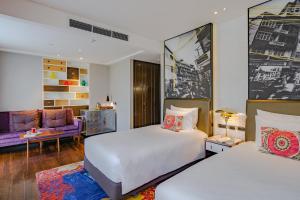 a bedroom with two beds and a living room at Hotel Indigo Bangkok Wireless Road by IHG in Bangkok