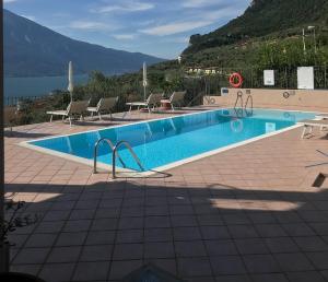 a large swimming pool with chairs and a view of the water at Apartments "VILLA IMELDA" in Limone sul Garda