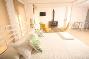 ein Schlafzimmer mit einem großen weißen Bett und gelben Stühlen in der Unterkunft APARTAMENTOS GORI SUITES HIDROMASAJE accesibles minusválidos in Villafranca del Cid