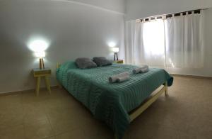 ein Schlafzimmer mit einem Bett mit einer grünen Decke und einem Fenster in der Unterkunft AQUA in Puerto Madryn