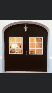 une porte de garage noir avec deux fenêtres. dans l'établissement MAISON HÔTEL SES PENYES, à Alaior