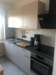 a kitchen with white cabinets and a stove top oven at Ferienwohnung Waschbärglück in Hahnenklee-Bockswiese +2 photos