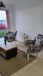 un soggiorno con due sedie, un tavolo e una finestra di Altos del Rey Apartamentos a San Salvador de Jujuy