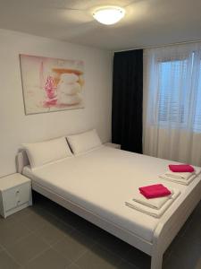 a large white bed with two red towels on it at Delfin Apartments in Crikvenica