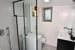 a white bathroom with a toilet and a sink at Deluxe Basement Apartment Bahai's Garden in Haifa