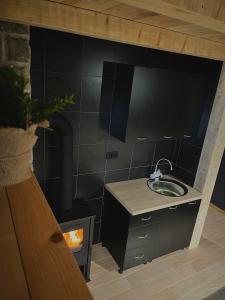 La salle de bains est pourvue d'un lavabo et d'un mur noir. dans l'établissement Apartman Kruna, à Kolašin