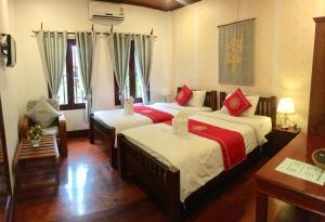 una camera con due letti con lenzuola rosse e bianche di Luang Prabang Pangkham Lodge a Luang Prabang